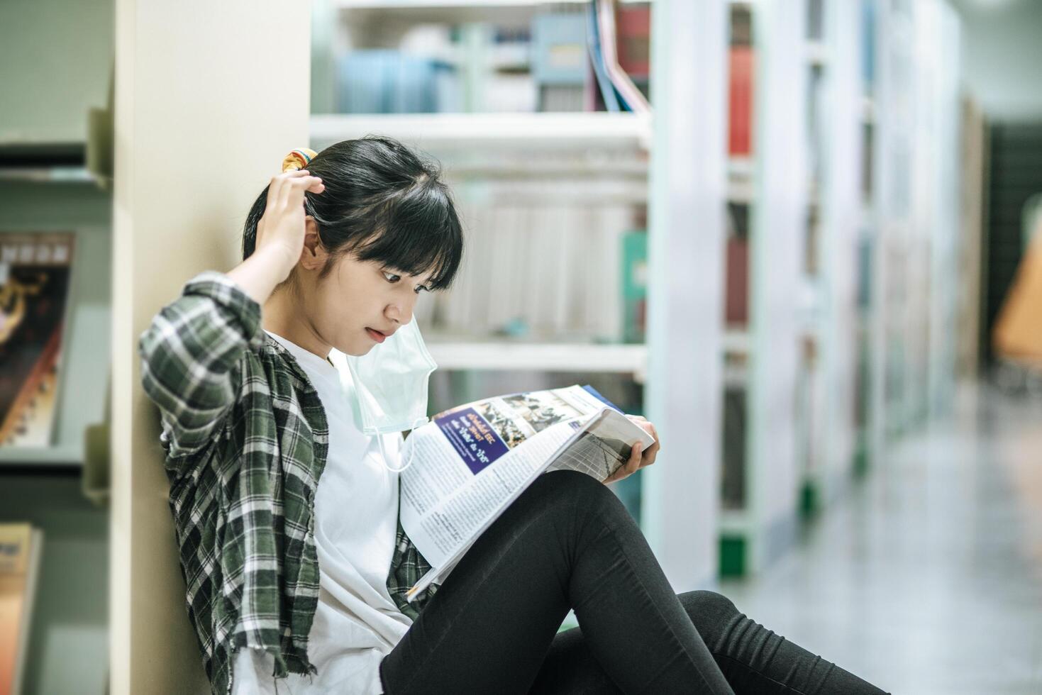 en kvinna som sitter och läser en bok i biblioteket. foto