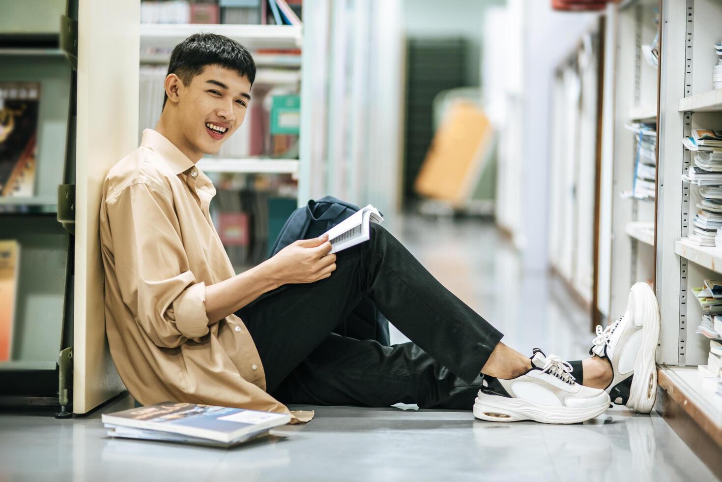 en man som sitter och läser en bok i biblioteket. foto