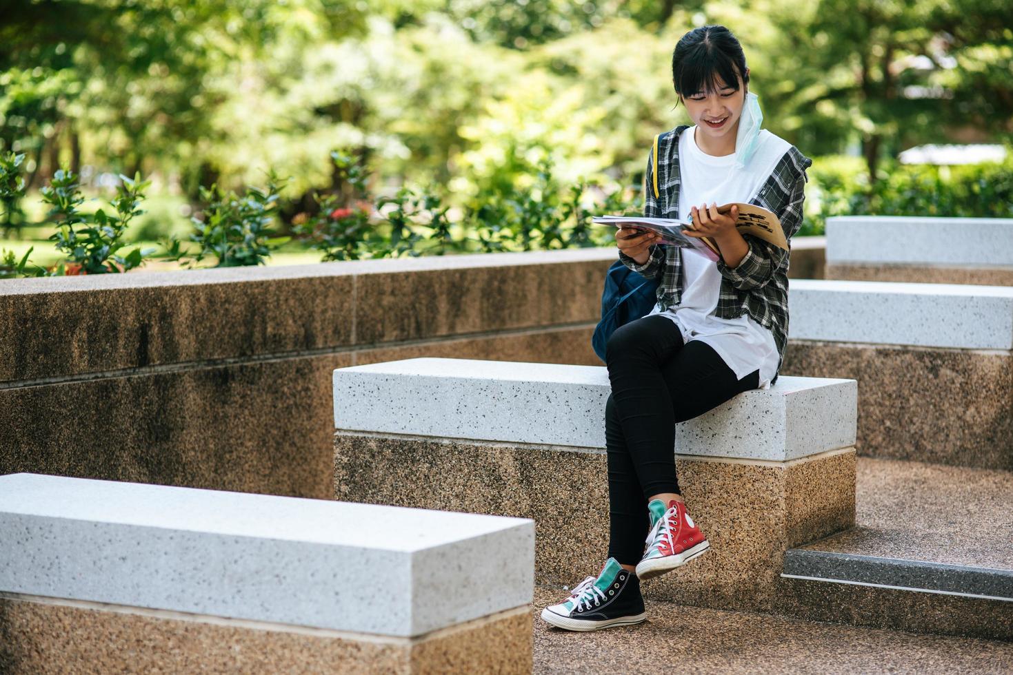 kvinnlig student sitter på trappan och läser en bok. foto