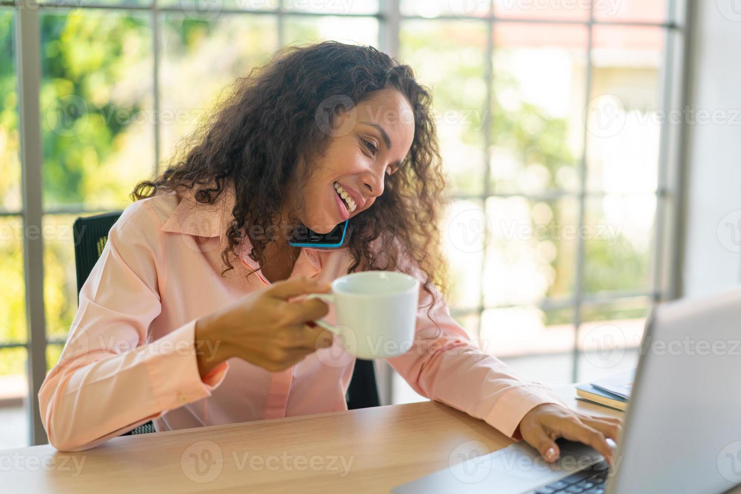 latinsk kvinna som arbetar med kaffekopp på arbetsyta foto