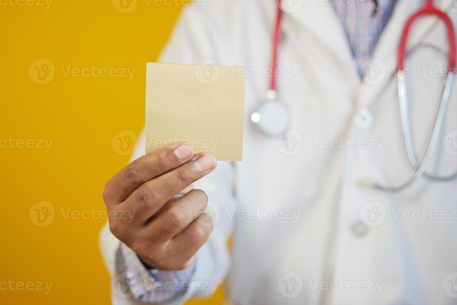 läkare hand håller en klisterlapp mot gul bakgrund foto