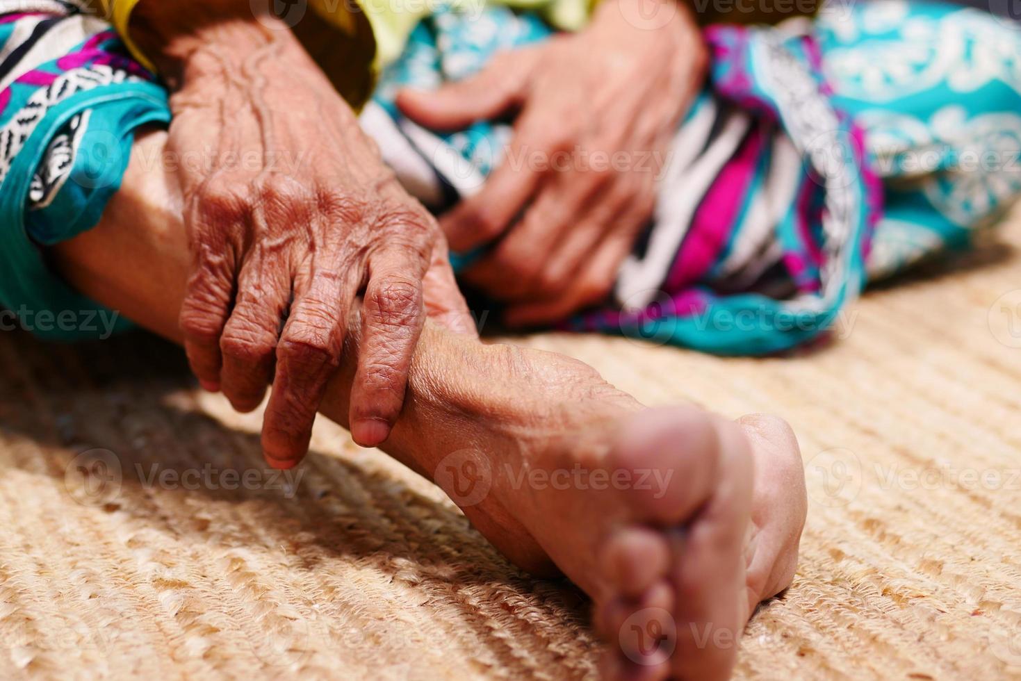 närbild på äldre kvinnors fötter och handmassage på skadeplatsen. foto