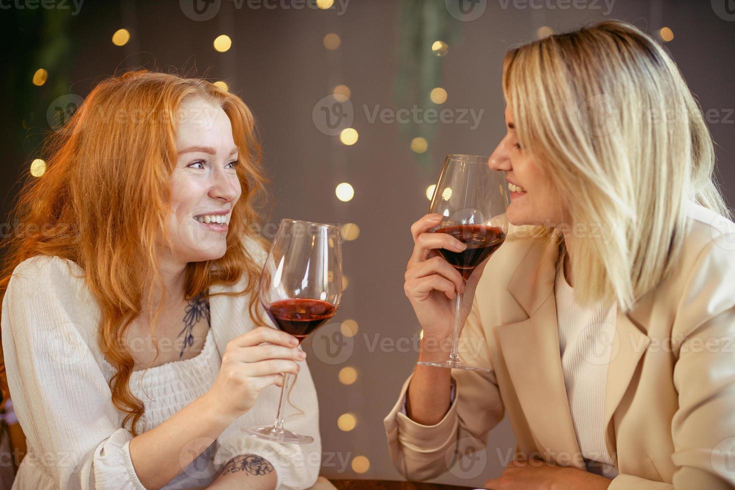 lesbiskt par äter middag på en restaurang. tjejer dricker vin och pratar foto