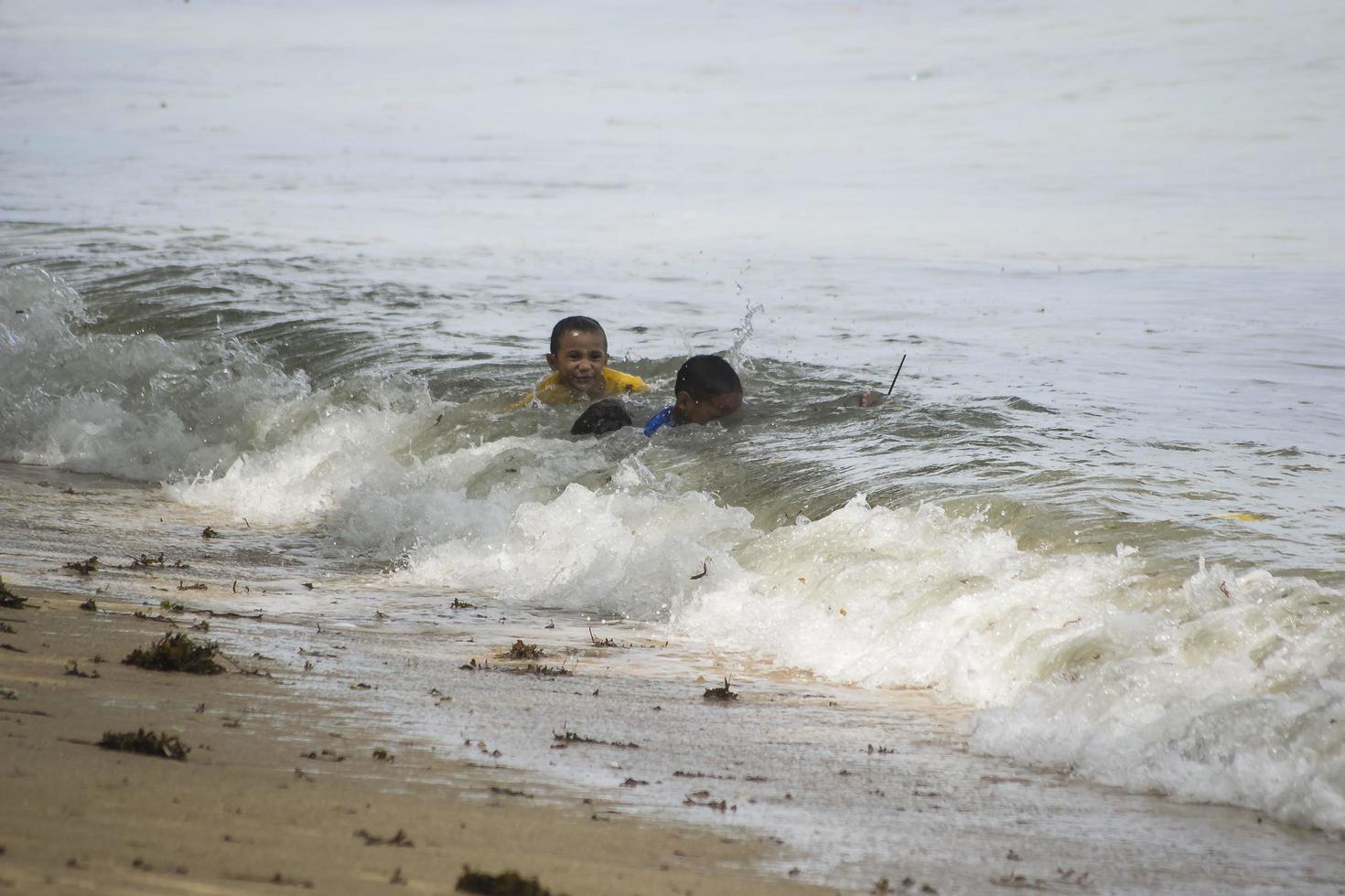 sorong, västra papua, indonesien, 12 december 2021. pojkar leker mot vågorna på stranden foto