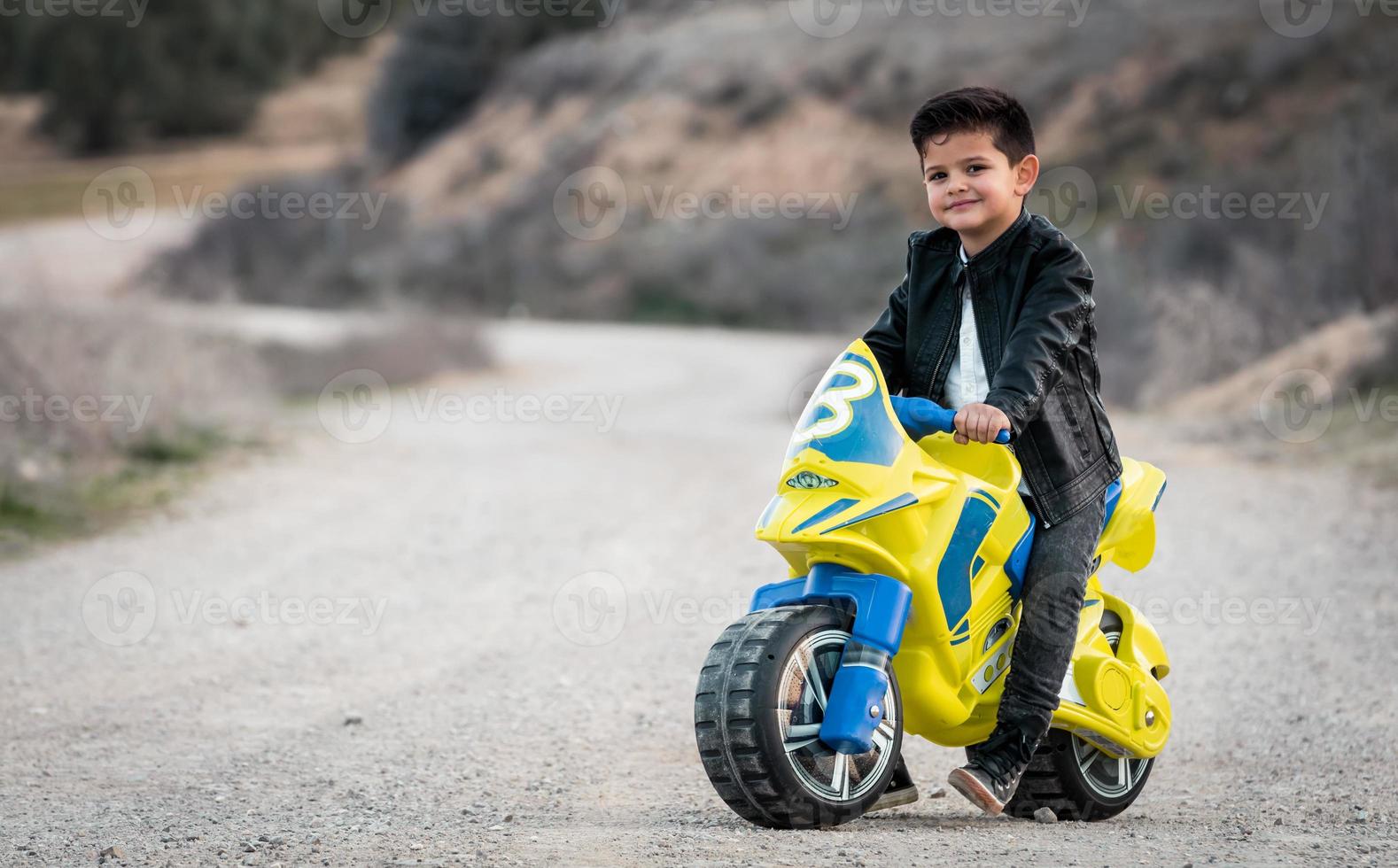 liten pojke som rider på motorcykelleksak foto