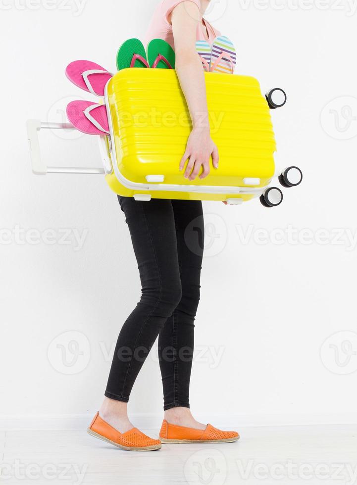 flicka med resväska isolerad på vit bakgrund. sommarlov. sommar flip -flops eller tofflor. resevalise eller väska. håna. kopiera utrymme. mall. tom. foto