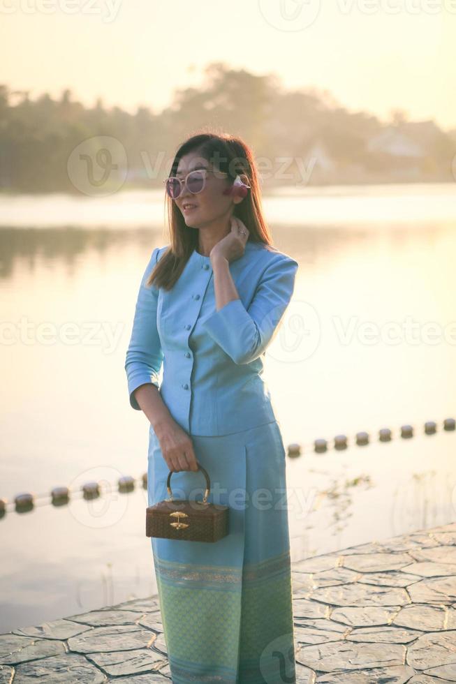 vacker asiatisk kvinna som bär thailändska traditionskläder står utomhus mot morgonljus foto