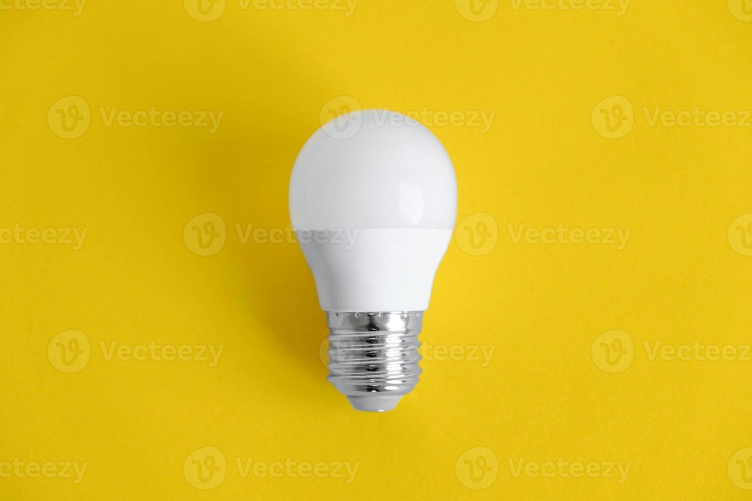 vit glödlampa på gul bakgrund foto