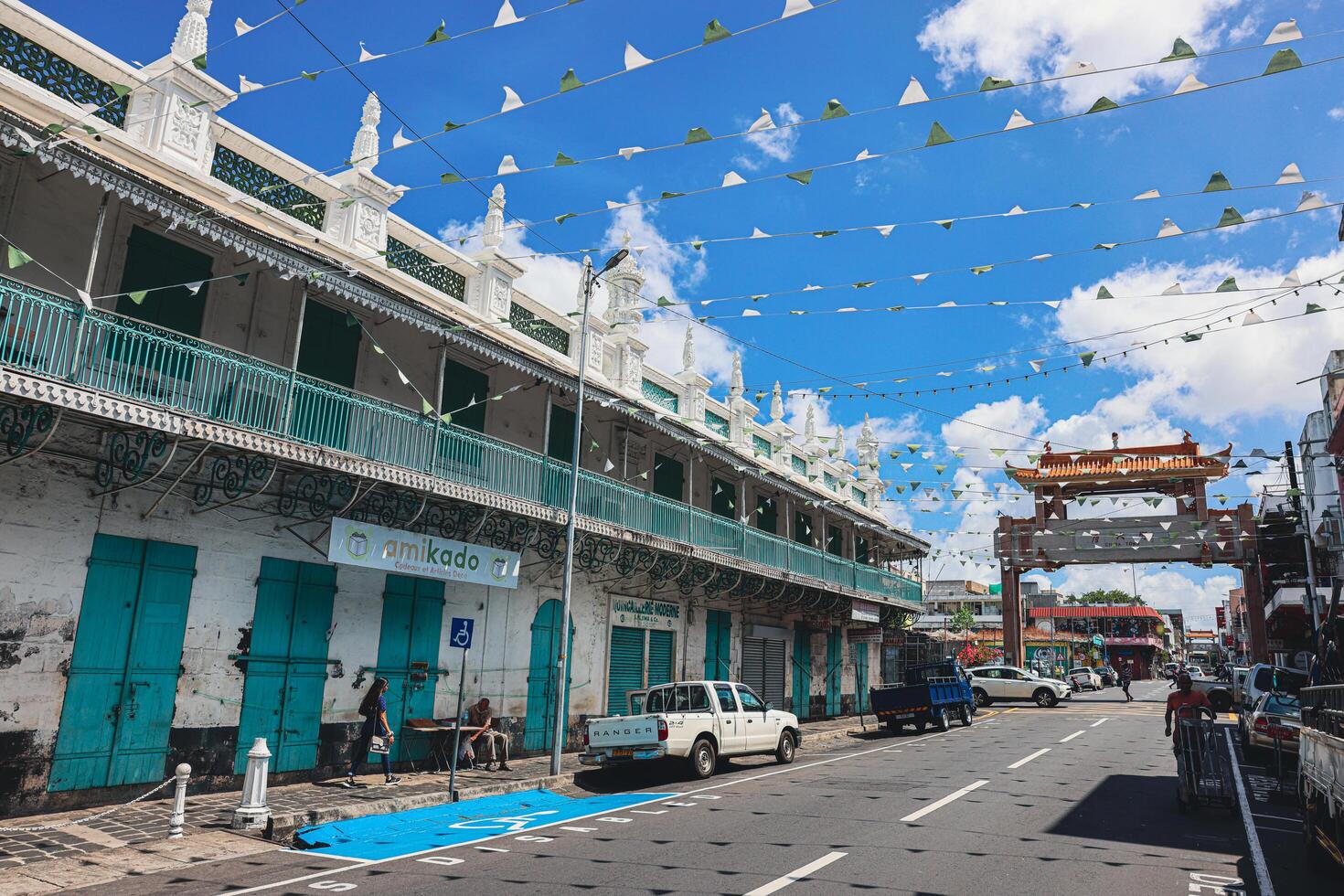 hamn louis, mauritius - januari 14, 2023 - en olika grupp av individer stående i främre av en byggnad, belägen i hamn Louis stad, Mauritius, med en framträdande moské i de bakgrund. foto