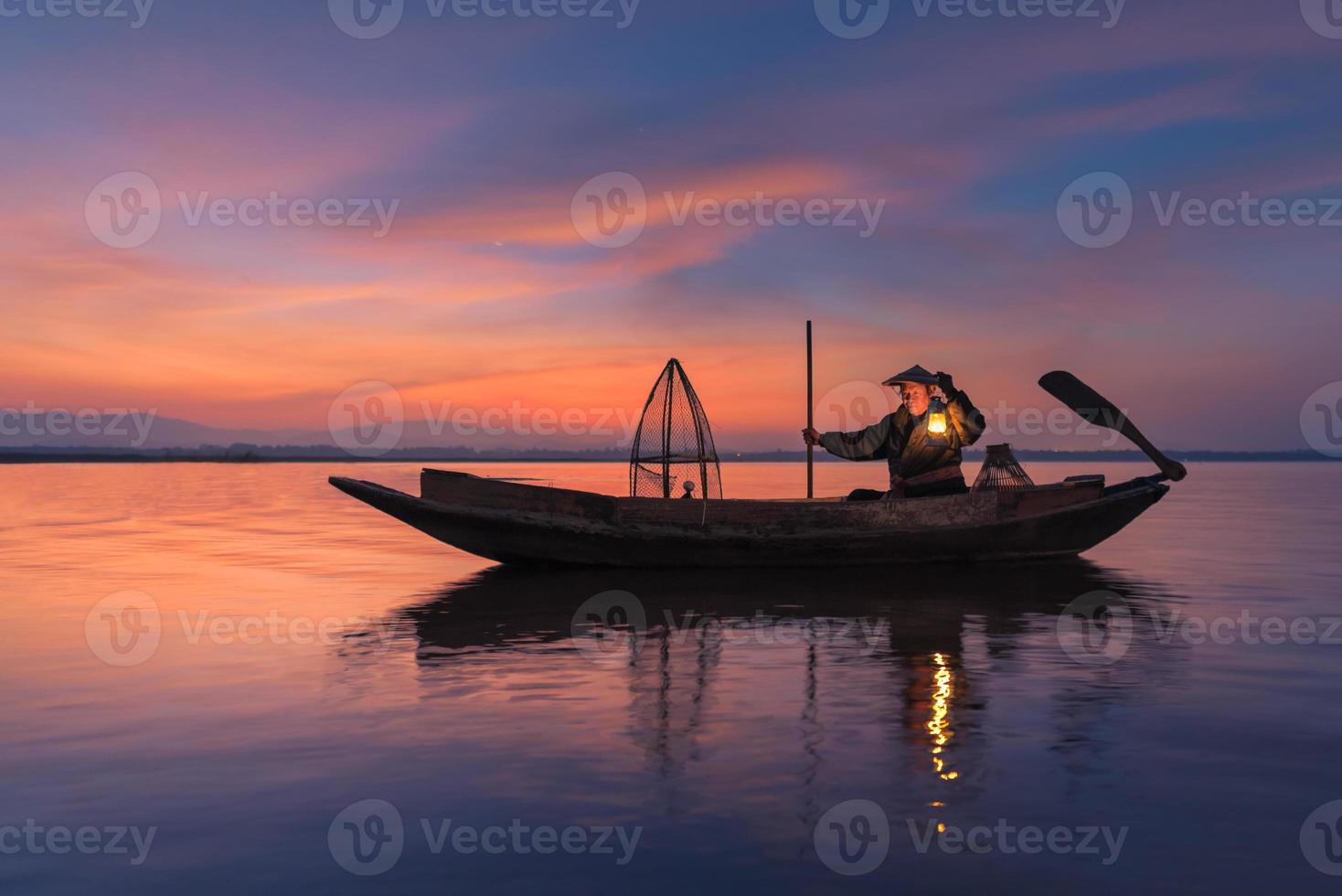 asiatisk fiskare med träbåt i naturfloden i början av soluppgången foto