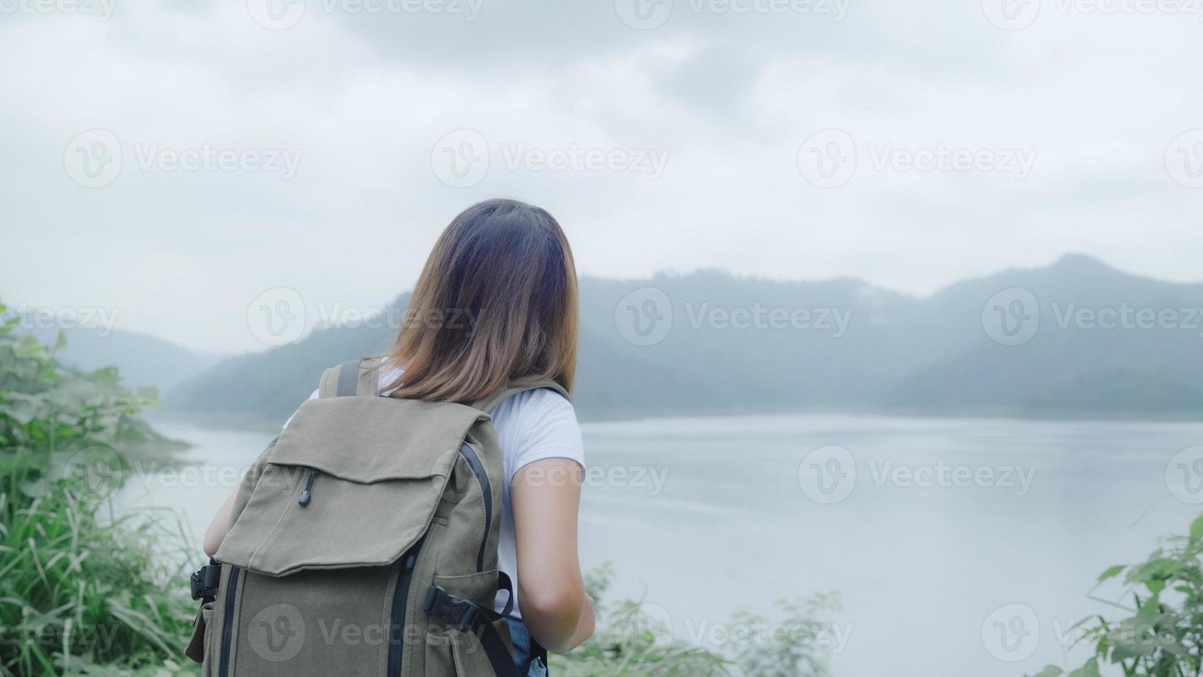 hiker backpacker kvinna på vandring äventyr känner frihet gå i skogen nära sjön i regnig dag. livsstil kvinnor reser slappna av koncept. foto