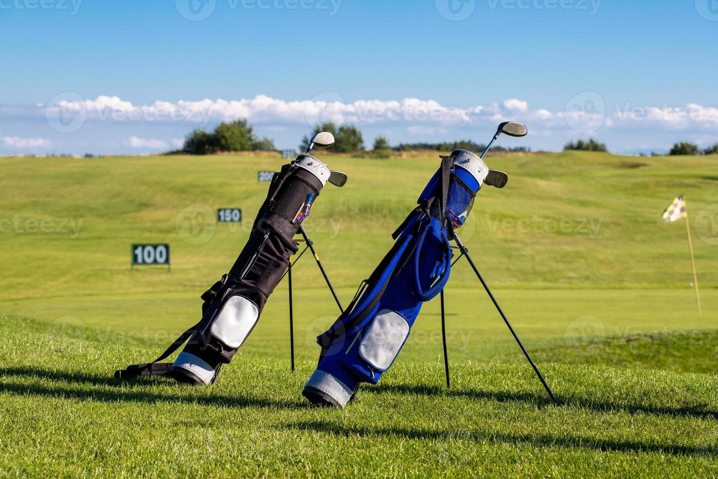 golfklubbor i påsar liggande på golfbanan en solig dag foto