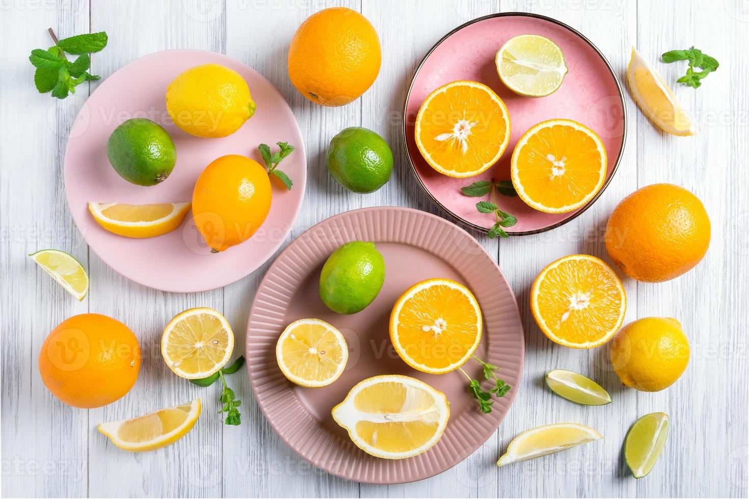 närbild av hela och skurna citrusfrukter på rosa keramiska tallrikar foto