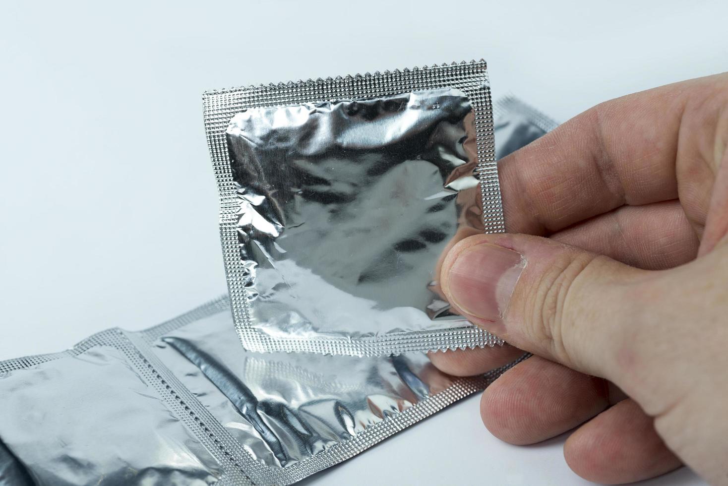 hand som håller en kondom, på en vit bakgrund. foto