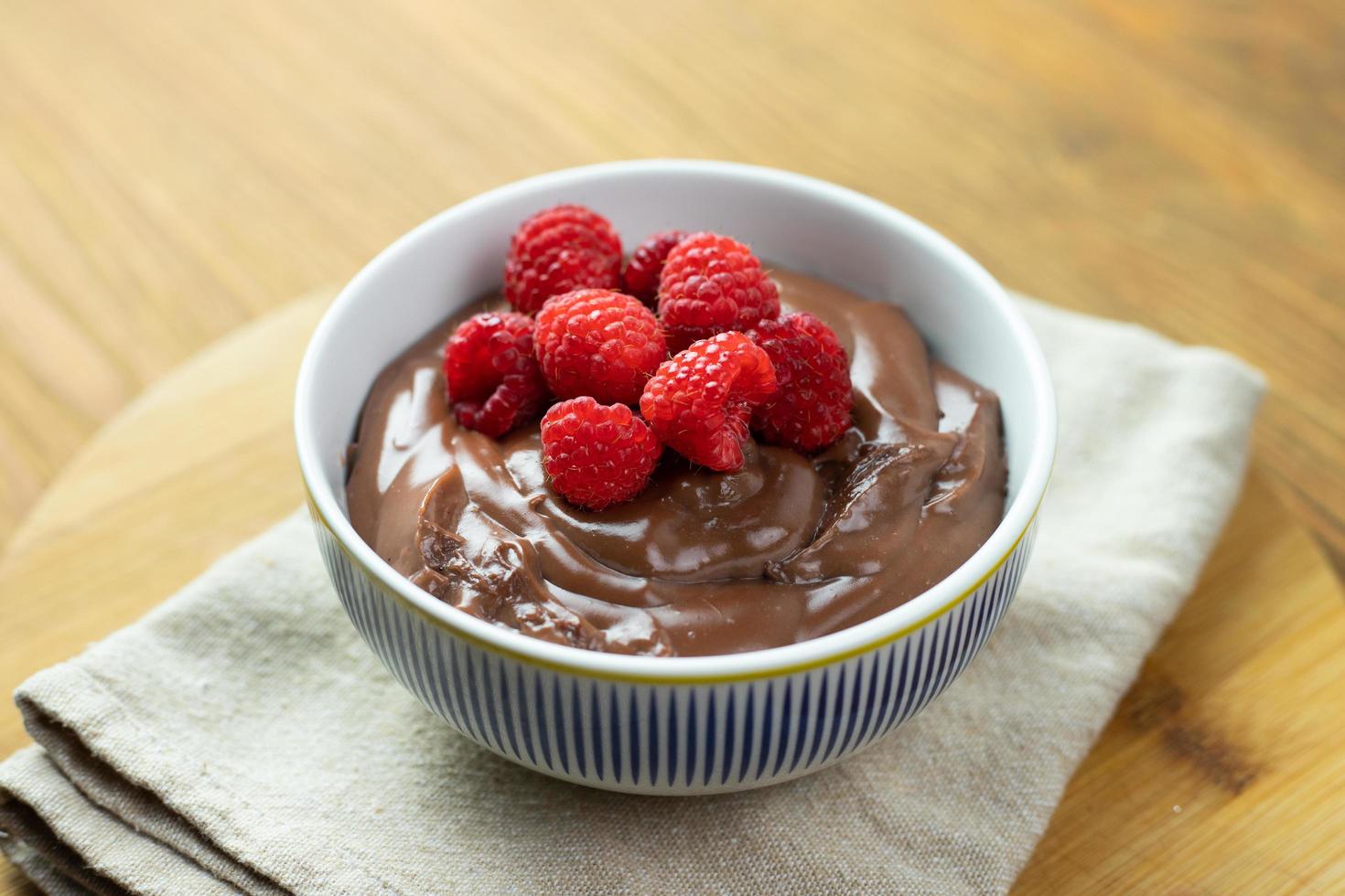 chokladpudding med hallon på ett träbord. foto