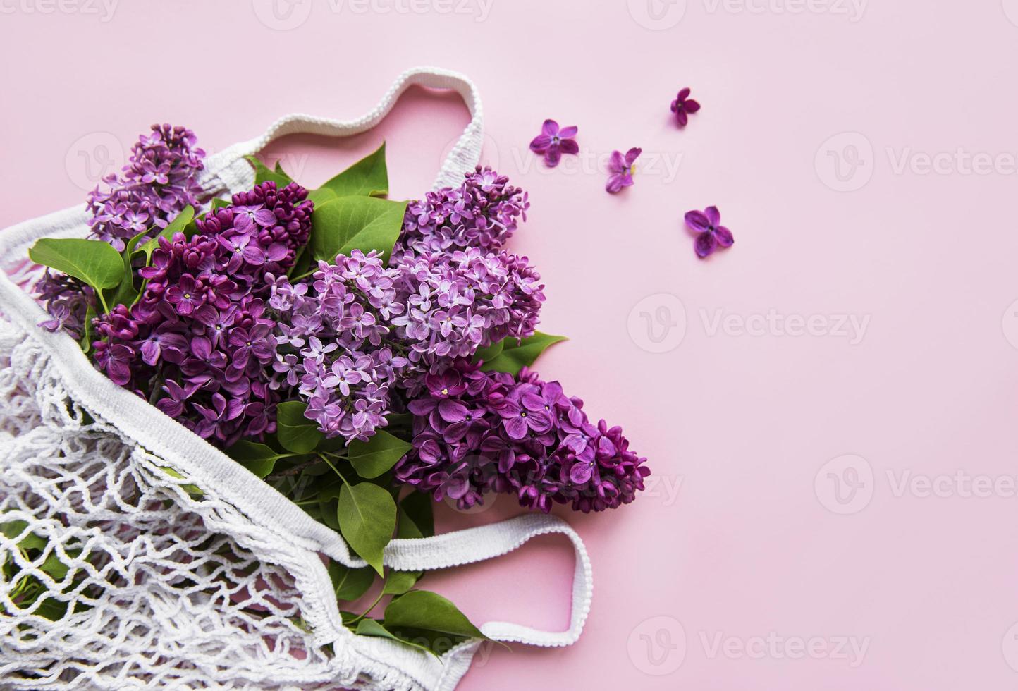 bukett lila i återanvändbar shopping eco mesh väska på rosa bakgrund. koncept ingen plast, noll avfall. kopiera utrymme ovanifrån mall för gratulationskort, vykort, inbjudan. foto