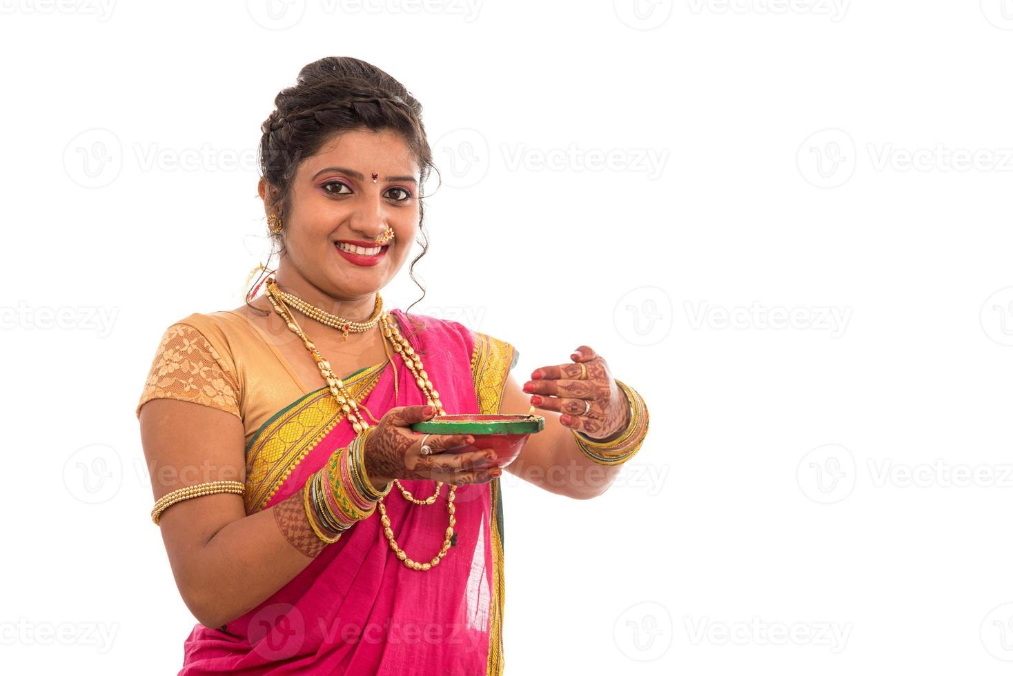 porträtt av en indisk traditionell flicka som håller pooja thali med diya under festival av ljus på vit bakgrund. diwali eller deepavali foto