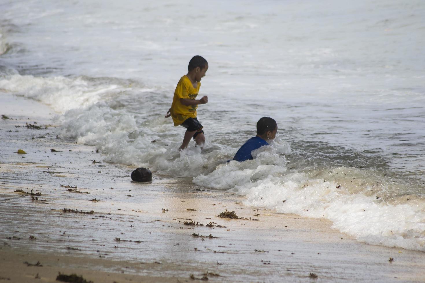 sorong, västra papua, indonesien, 12 december 2021. pojkar leker mot vågorna på stranden foto