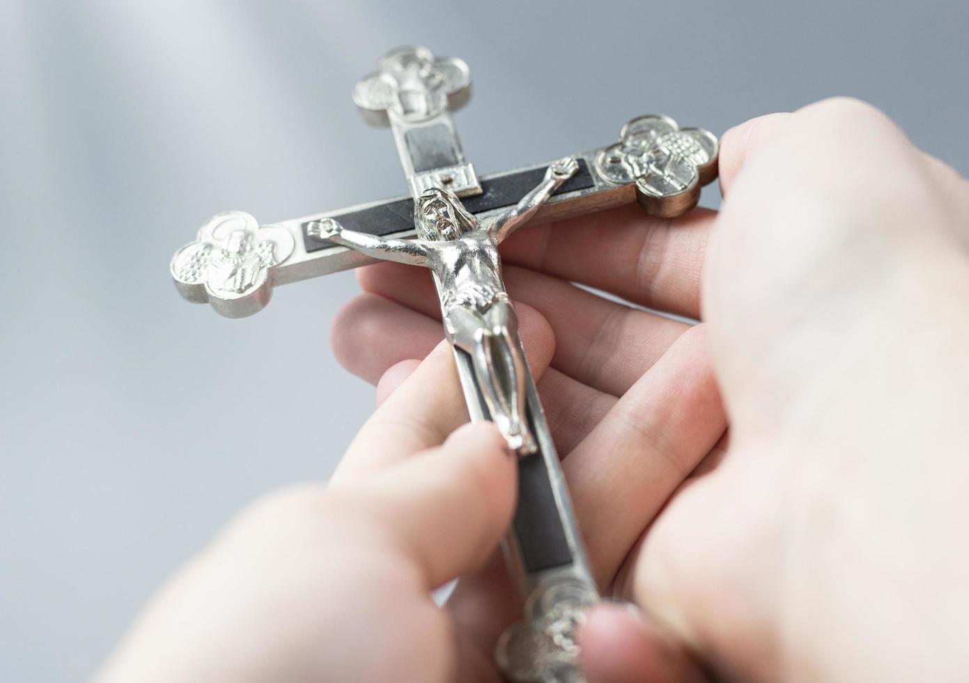 kristna korset hålls i händerna. symbol för religiös bön. korsfäste Jesus. foto