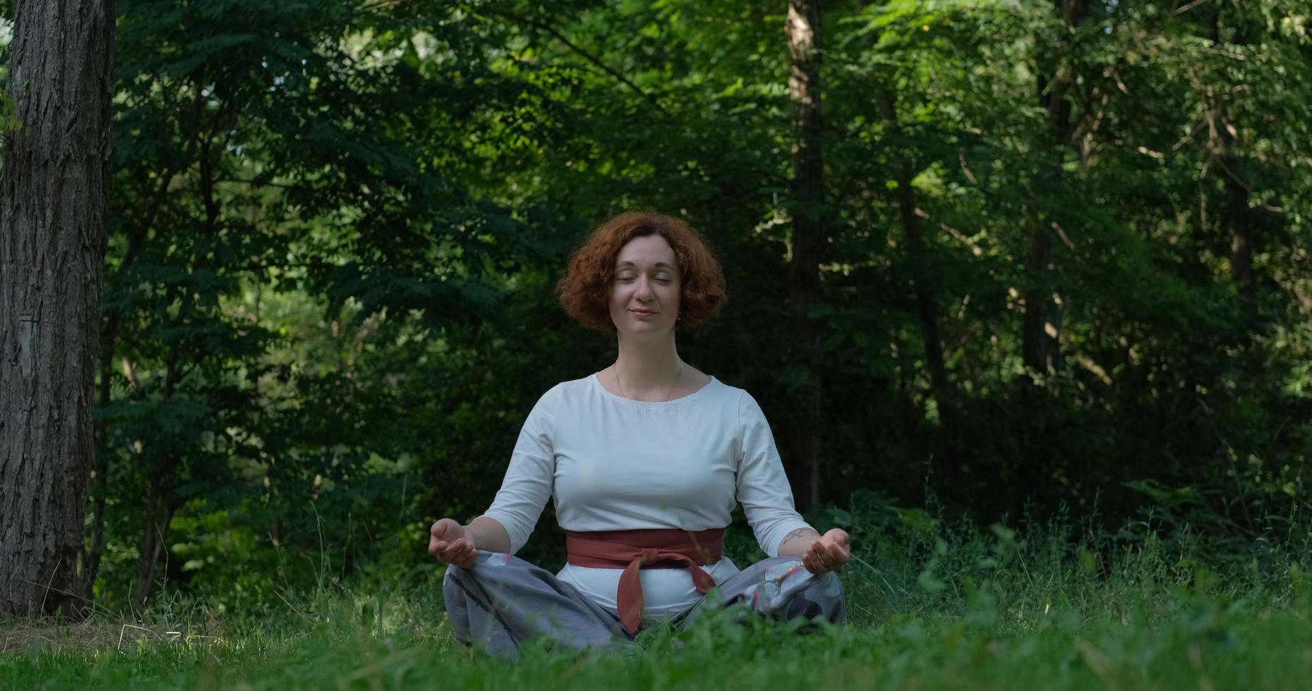 kvinna som utövar qigong och meditation i sommarparken eller skogen foto