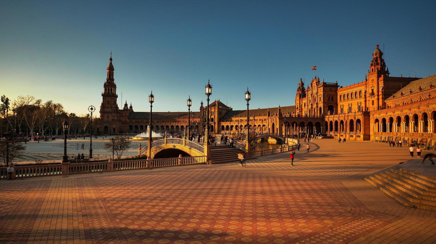 Sevilla, Spanien - 20 februari 2020 - turister som promenerar på Plaza de España med arkitekturdetaljer vid solnedgången i Sevillas centrum. foto
