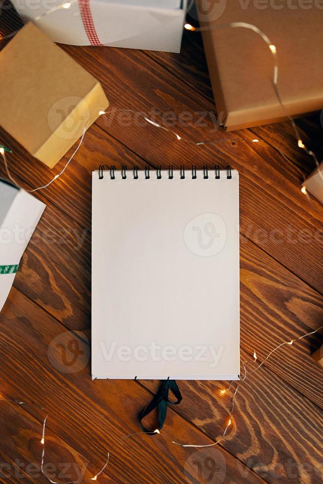 platt läggning av tom anteckningsbok och presentförpackningar på träbordsbakgrund. foto