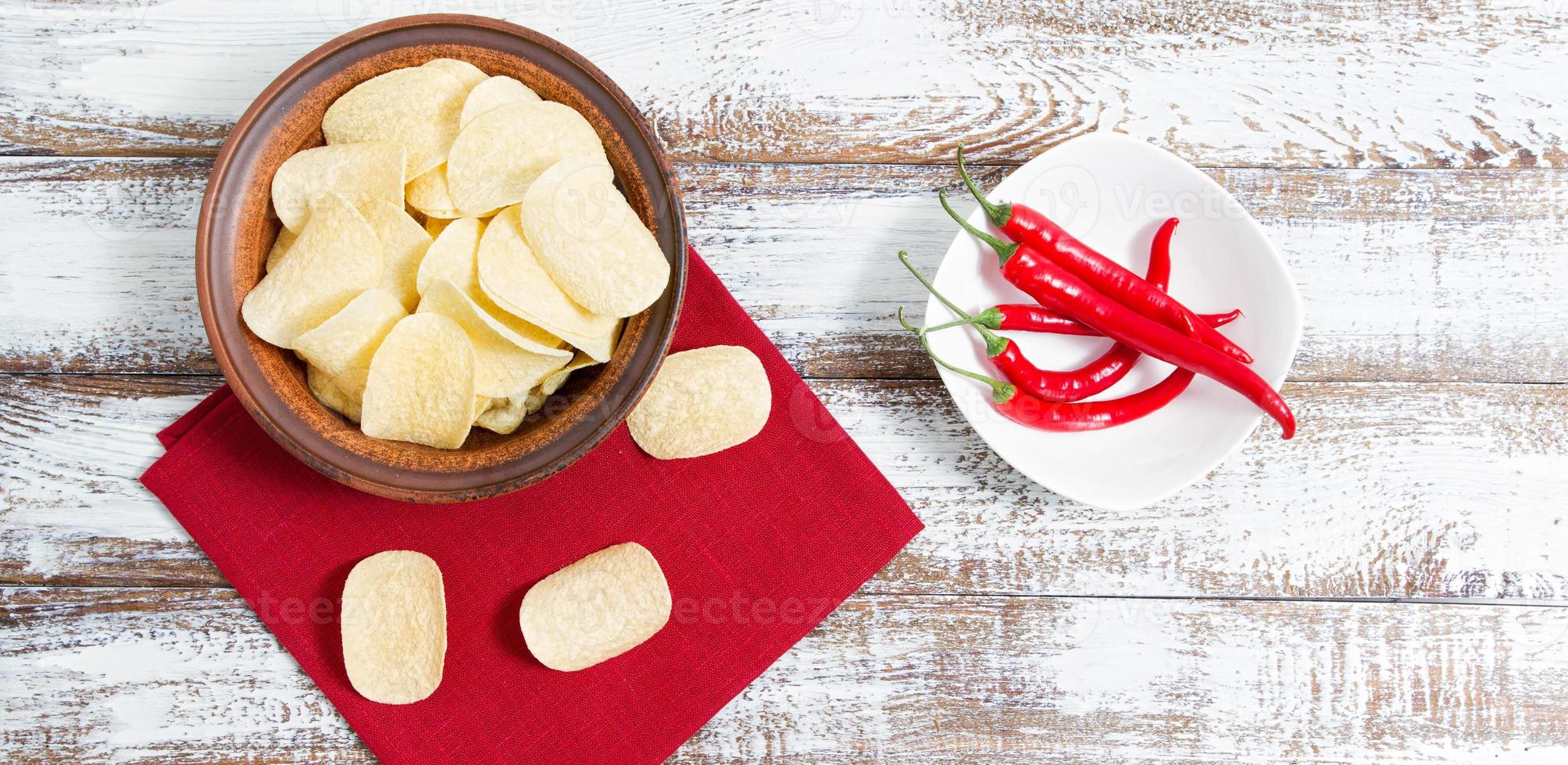 mock up potatischips på tallrik, varm peppar och röd servett på träbord - kopieringsutrymme foto