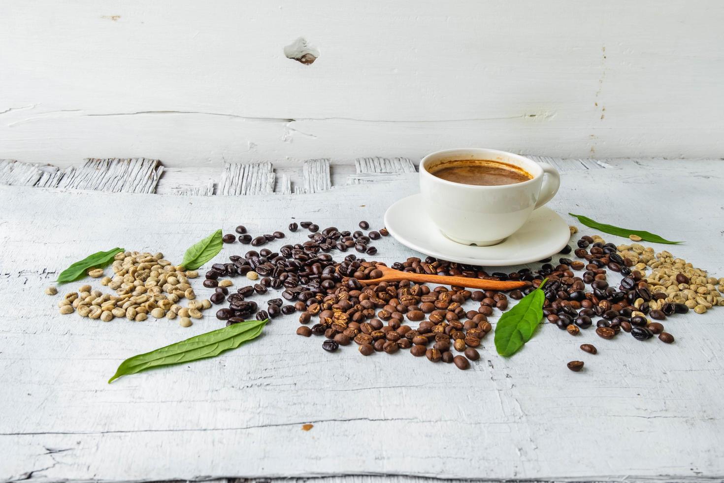 kaffekopp och kaffebönor på vit trä bakgrund foto