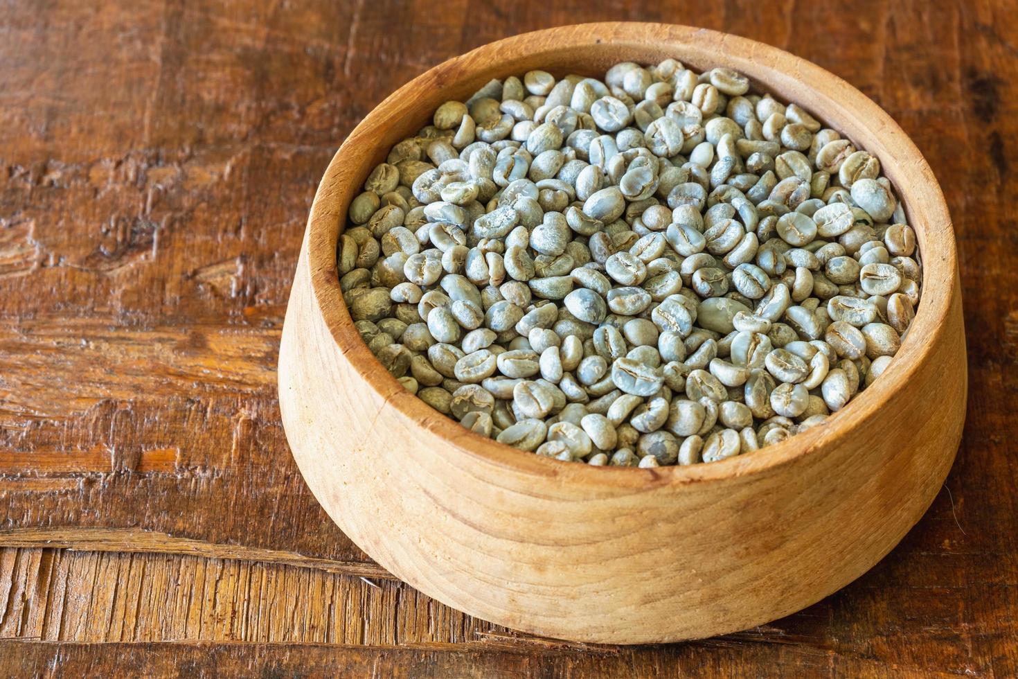 orostade gröna kaffebönor i en träskål foto