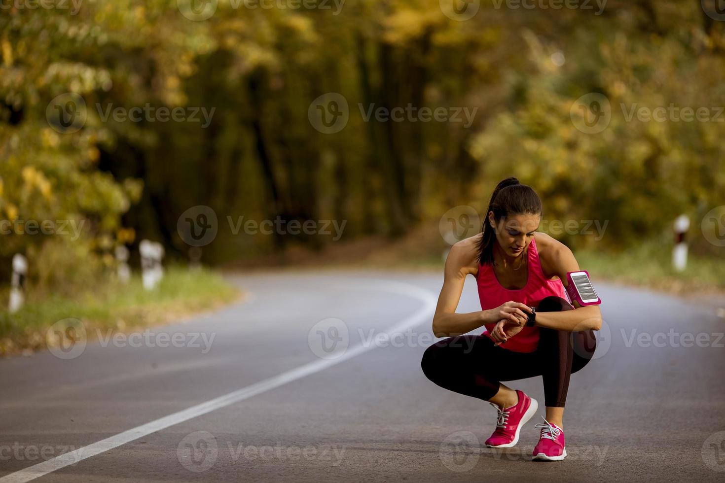 ung kvinna har en paus under träning i höstskogen foto