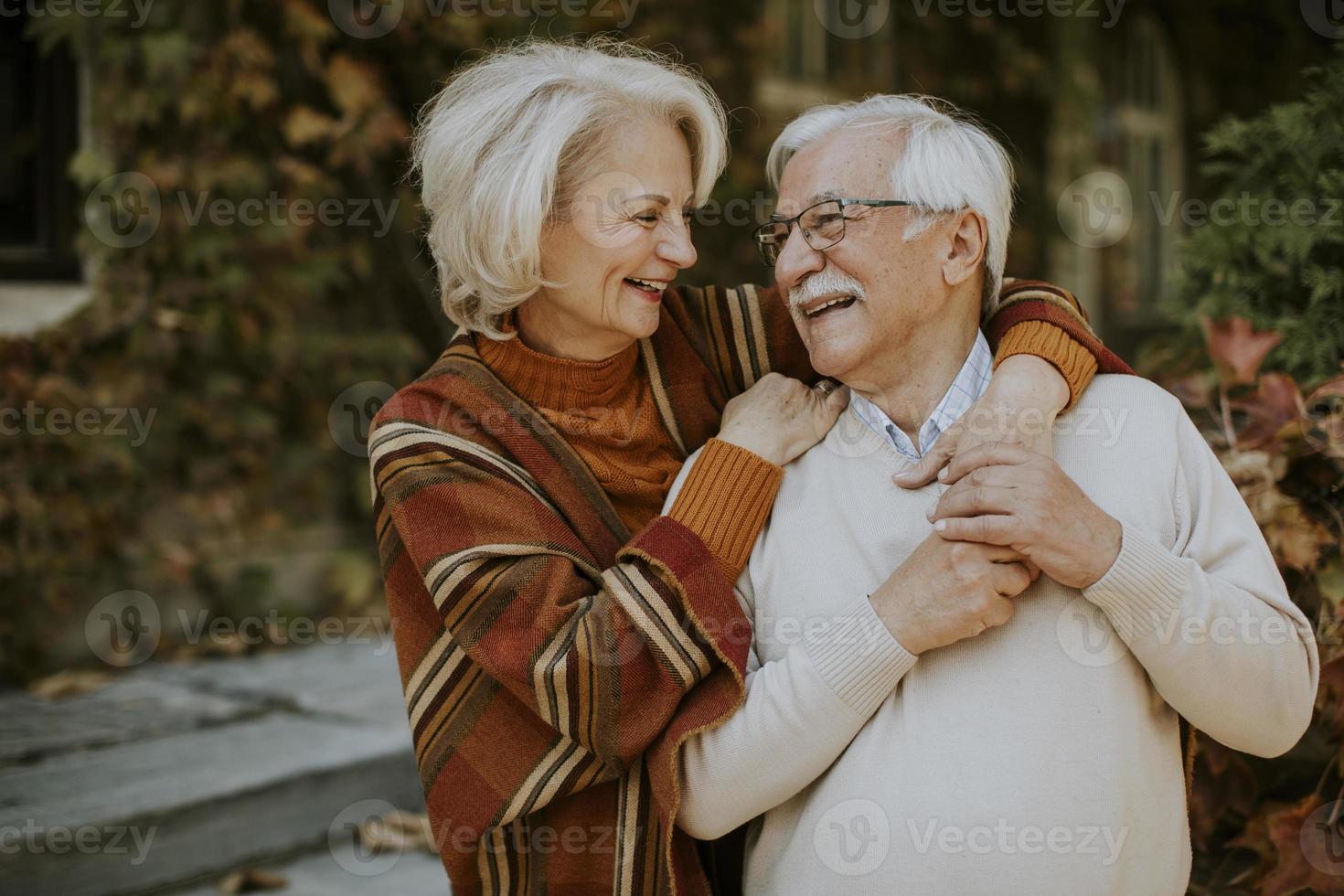 senior par omfamnar i höst park foto