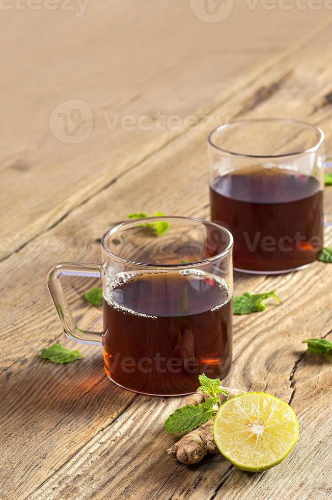 kopp te med ingefära, citron och mynta på träbord foto