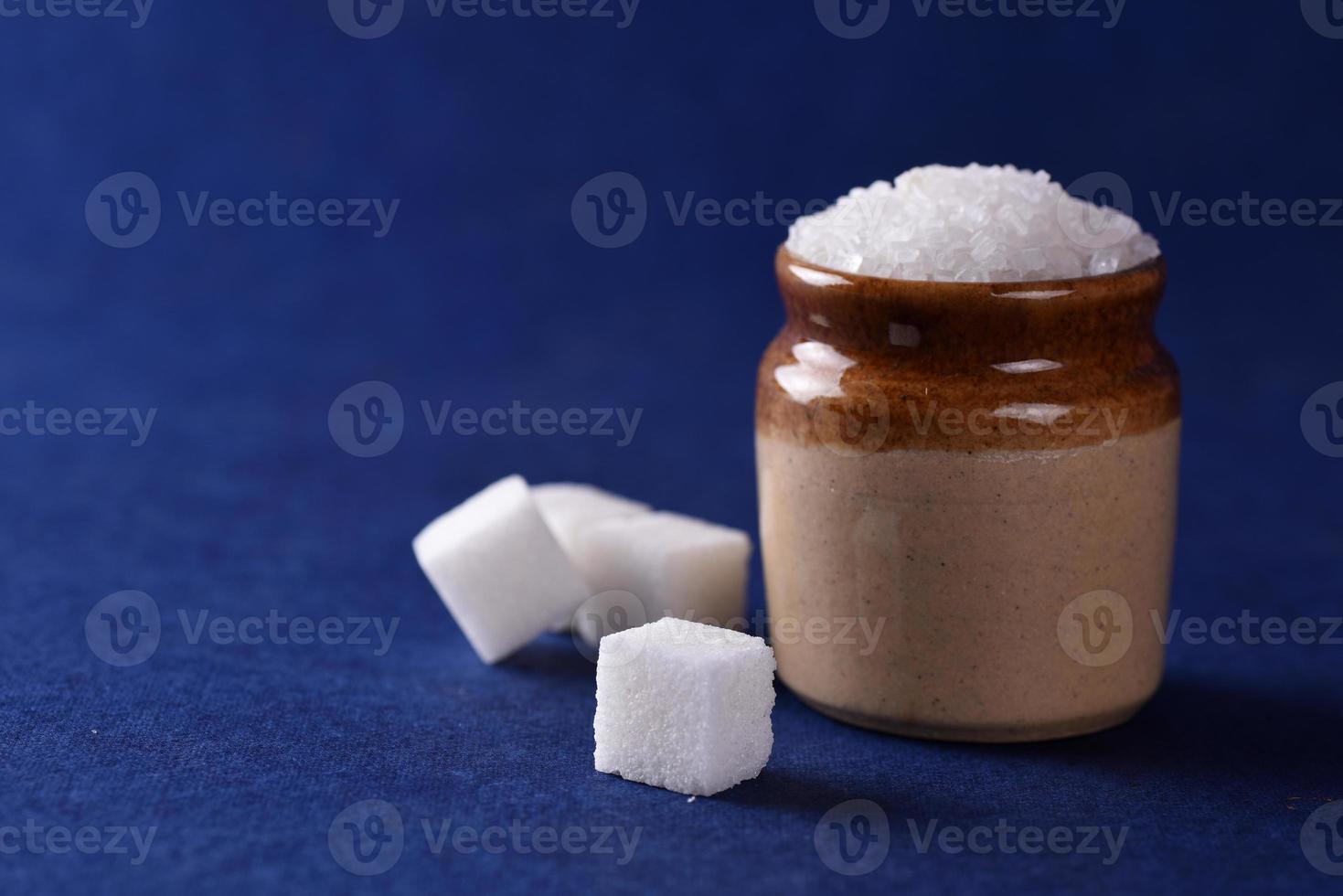 socker. vitt strösocker och raffinerat socker på en blå bakgrund foto