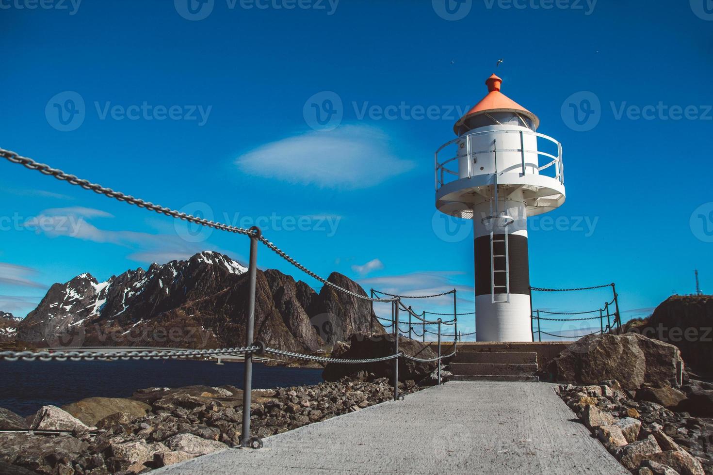 fyren på piren i bakgrunden av bergen och den blå himlen på Lofotenöarna. plats för text eller reklam foto
