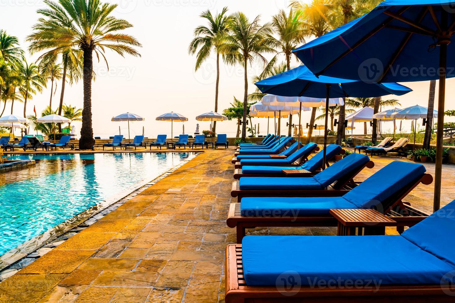 palmträd med paraplystol pool i lyxhotell resort vid soluppgången foto