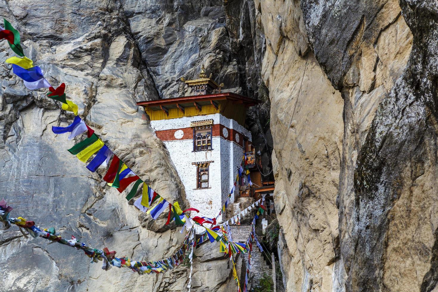 böneflaggor och ett litet kloster i bergen runt tigerboet kloster eller taktshang goemba i paro, bhutan, asien foto