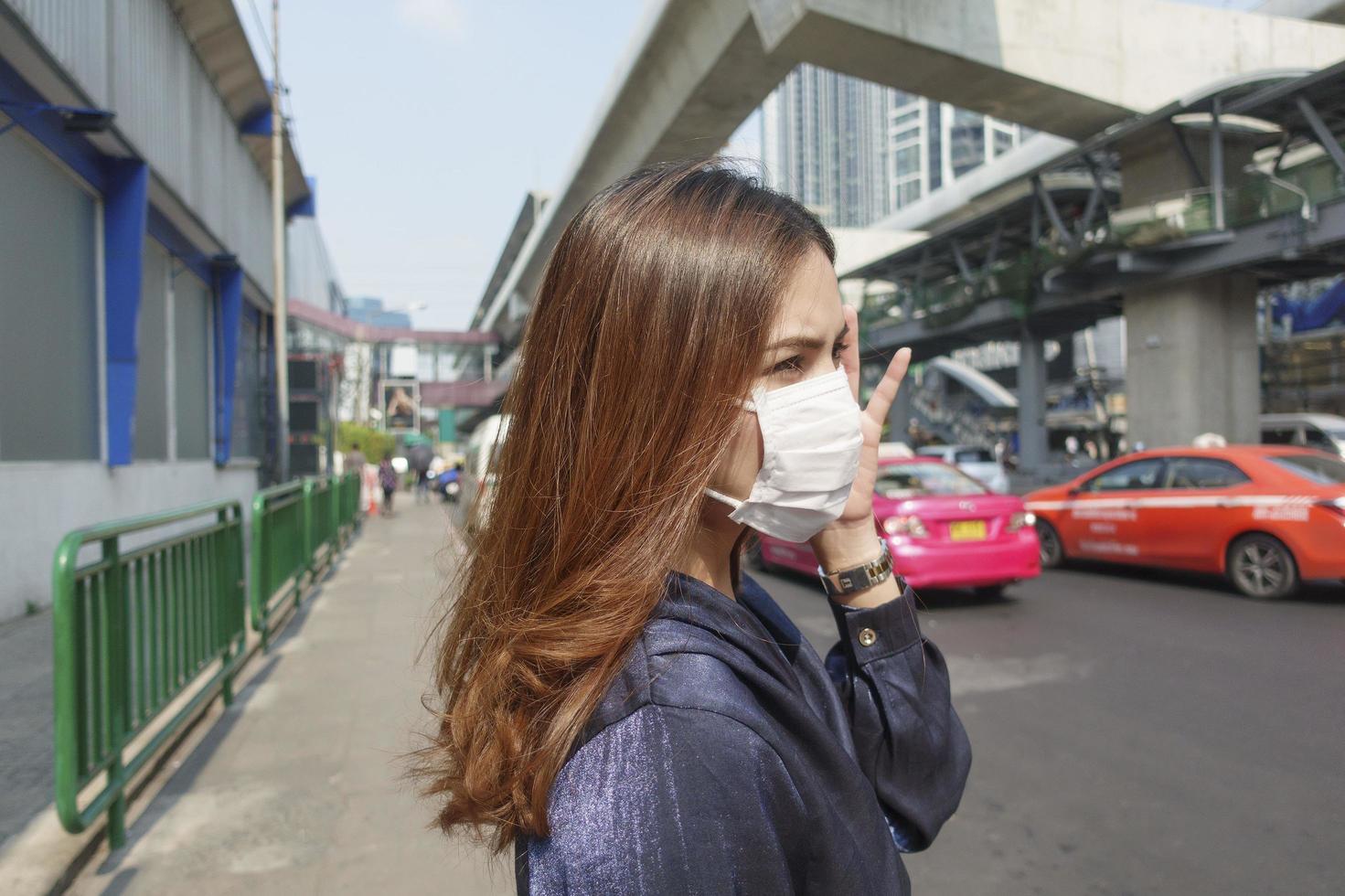 vacker kvinna bär anti damm mask skydda luftföroreningar och pm 2,5 på gata staden foto