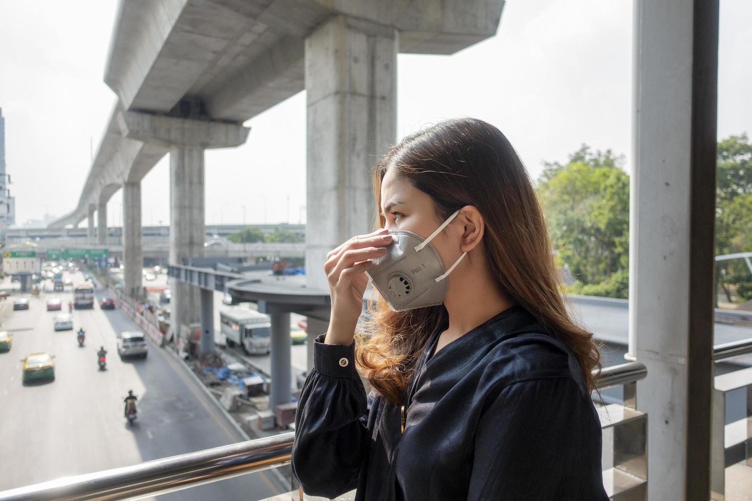 vacker kvinna bär anti damm mask skydda luftföroreningar och pm 2,5 på gata staden foto