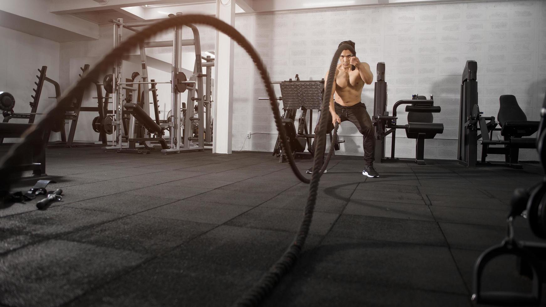 asiatisk atletisk man med rep gör träning i gymmet foto