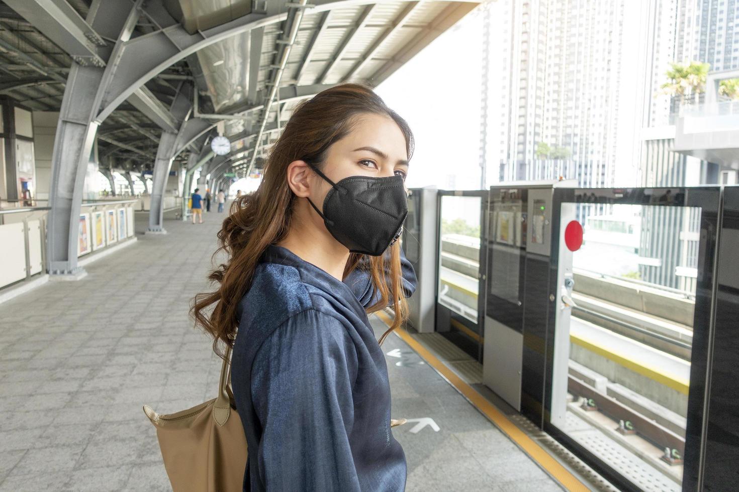 vacker kvinna bär anti damm mask skydda luftföroreningar och pm 2,5 på gata staden foto