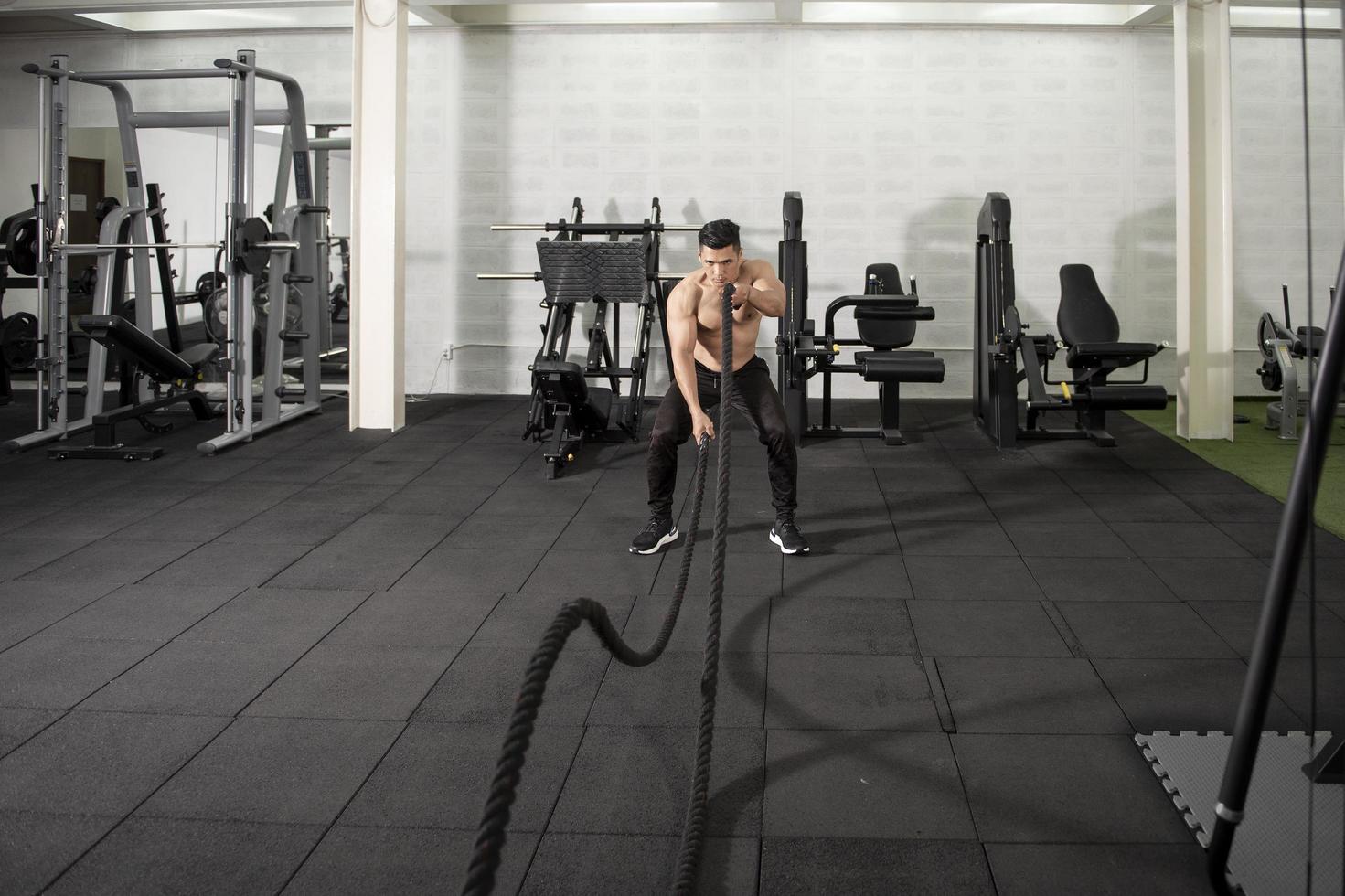 asiatisk atletisk man med rep gör träning i gymmet foto