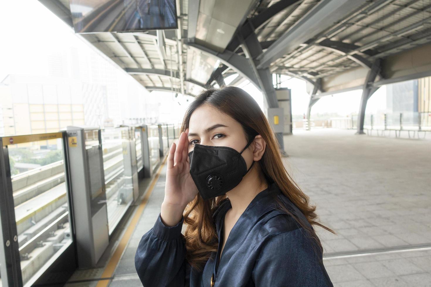 vacker kvinna bär anti damm mask skydda luftföroreningar och pm 2,5 på gata staden foto