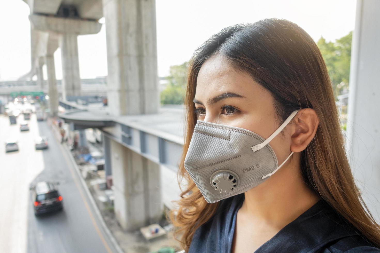 vacker kvinna bär anti damm mask skydda luftföroreningar och pm 2,5 på gata staden foto