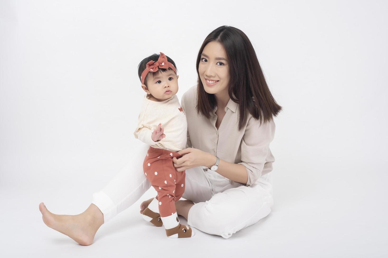 asiatisk mamma och bedårande flicka är glada på vit bakgrund foto