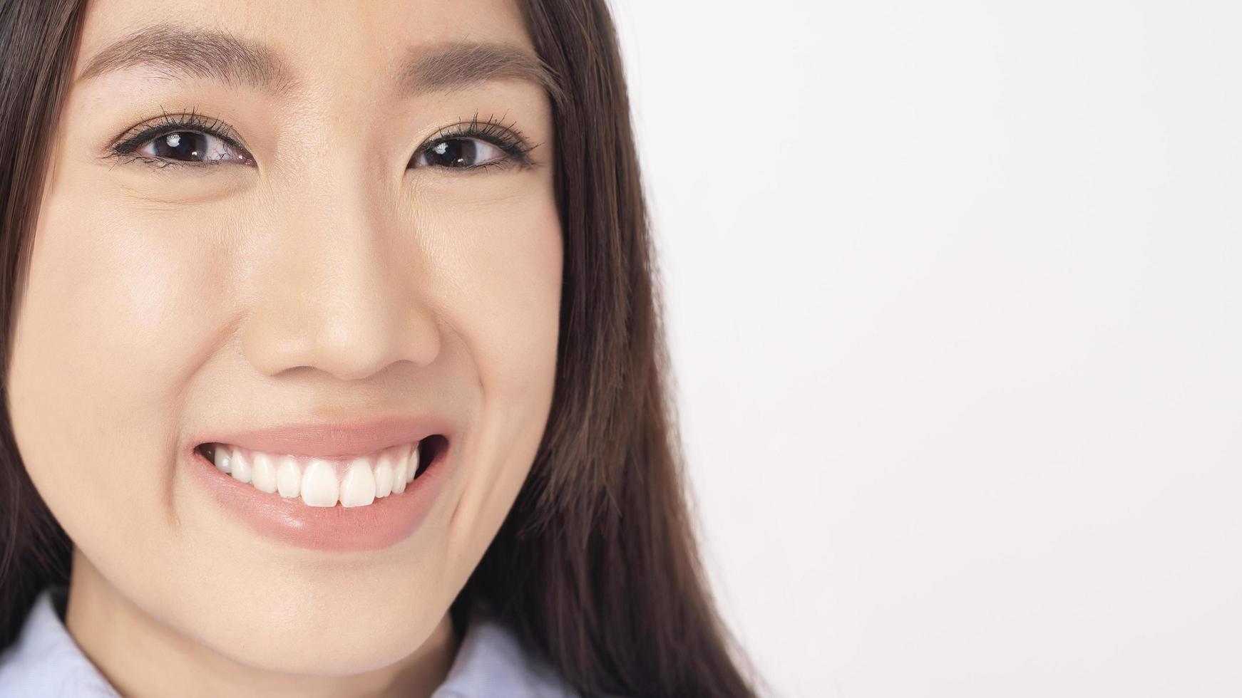 närbild av asiatisk kvinna med vackra tänder på vit bakgrund foto