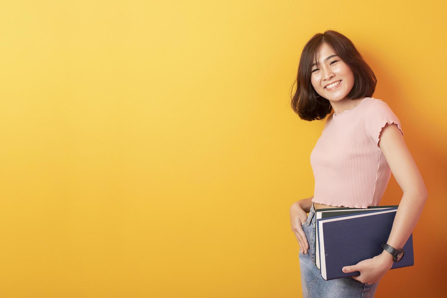 vacker asiatisk kvinna universitetsstudent glad på gul bakgrund foto