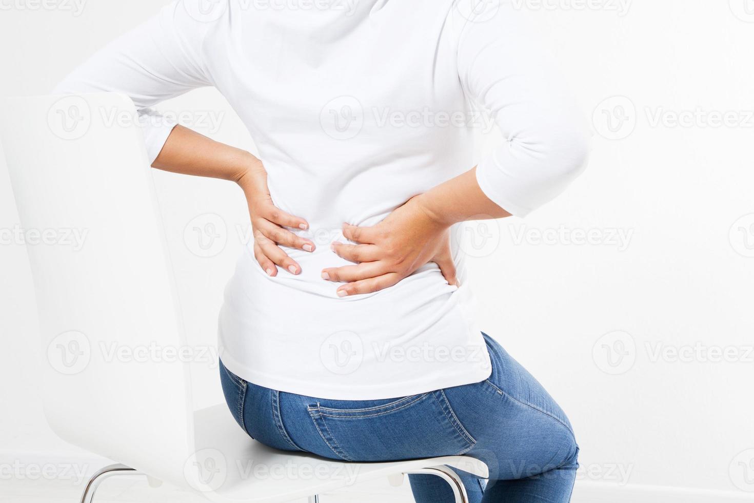 medelålders svart kvinna som lider av ryggvärk på stol foto