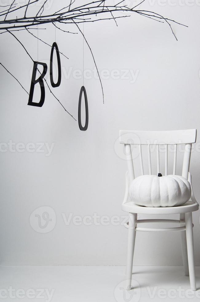 halloween trädgren med en vit pumpa på en stol på en vit bakgrund foto