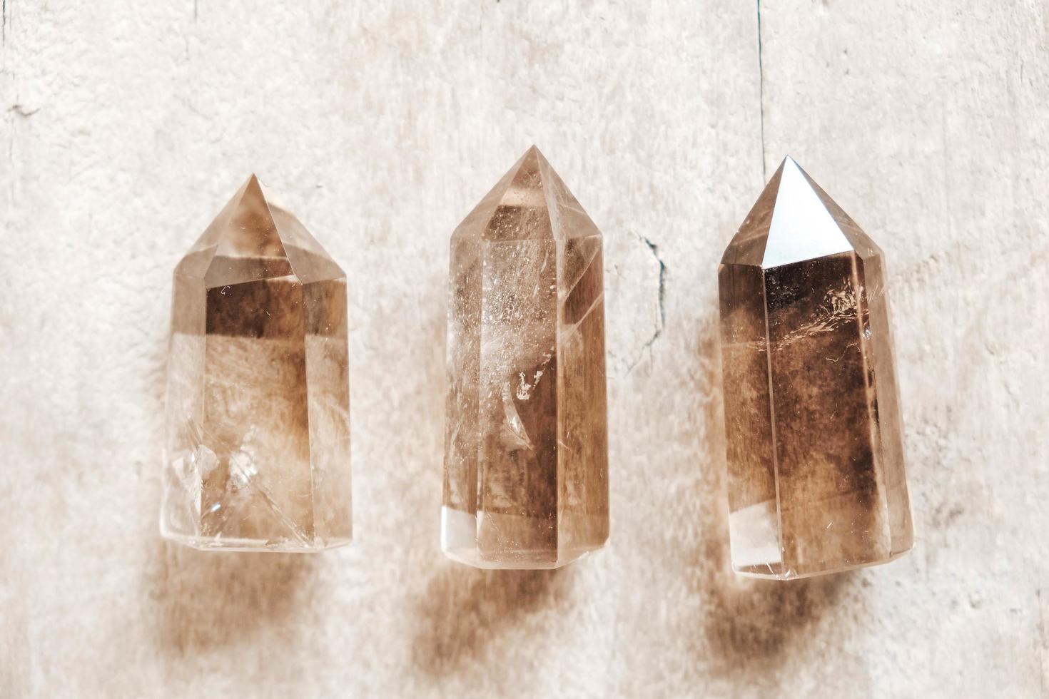 tre rökiga naturliga kvartskristaller på träbakgrund foto