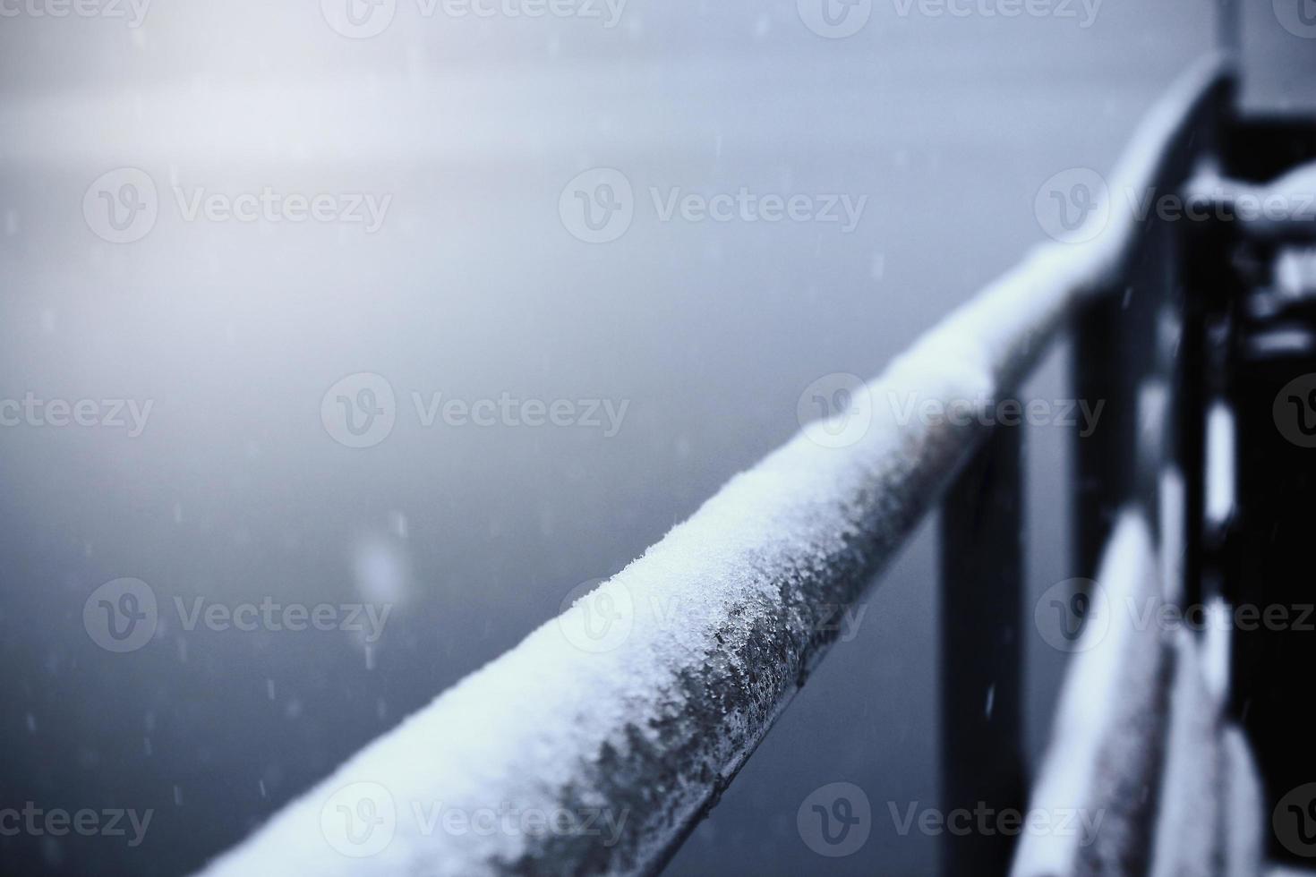 metall ledstång i snö med fallande snöflingor foto